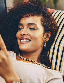 Shot of an attractive young woman using her cellphone while relaxing on the sofa at home